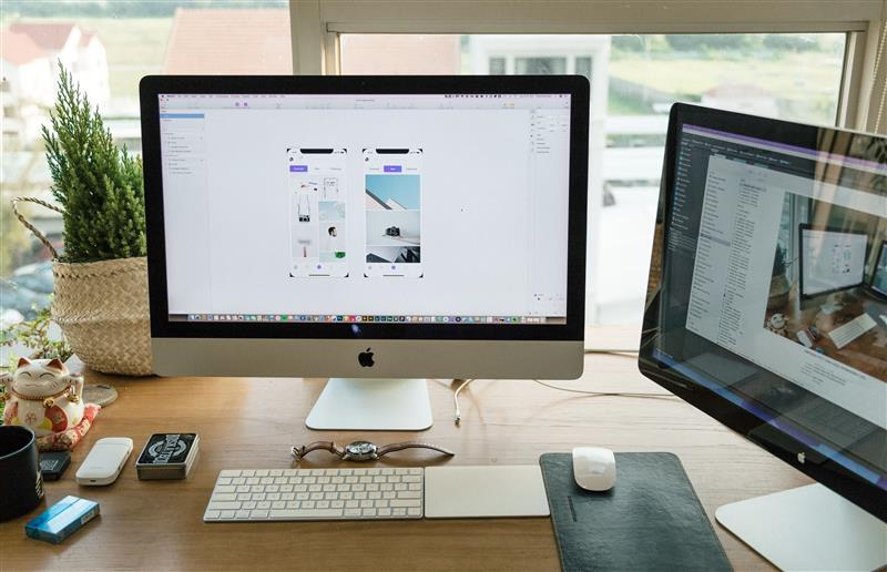 The Invisible Redesign article cover: designer workspace with an iMac showing mobile app screens in a design tool